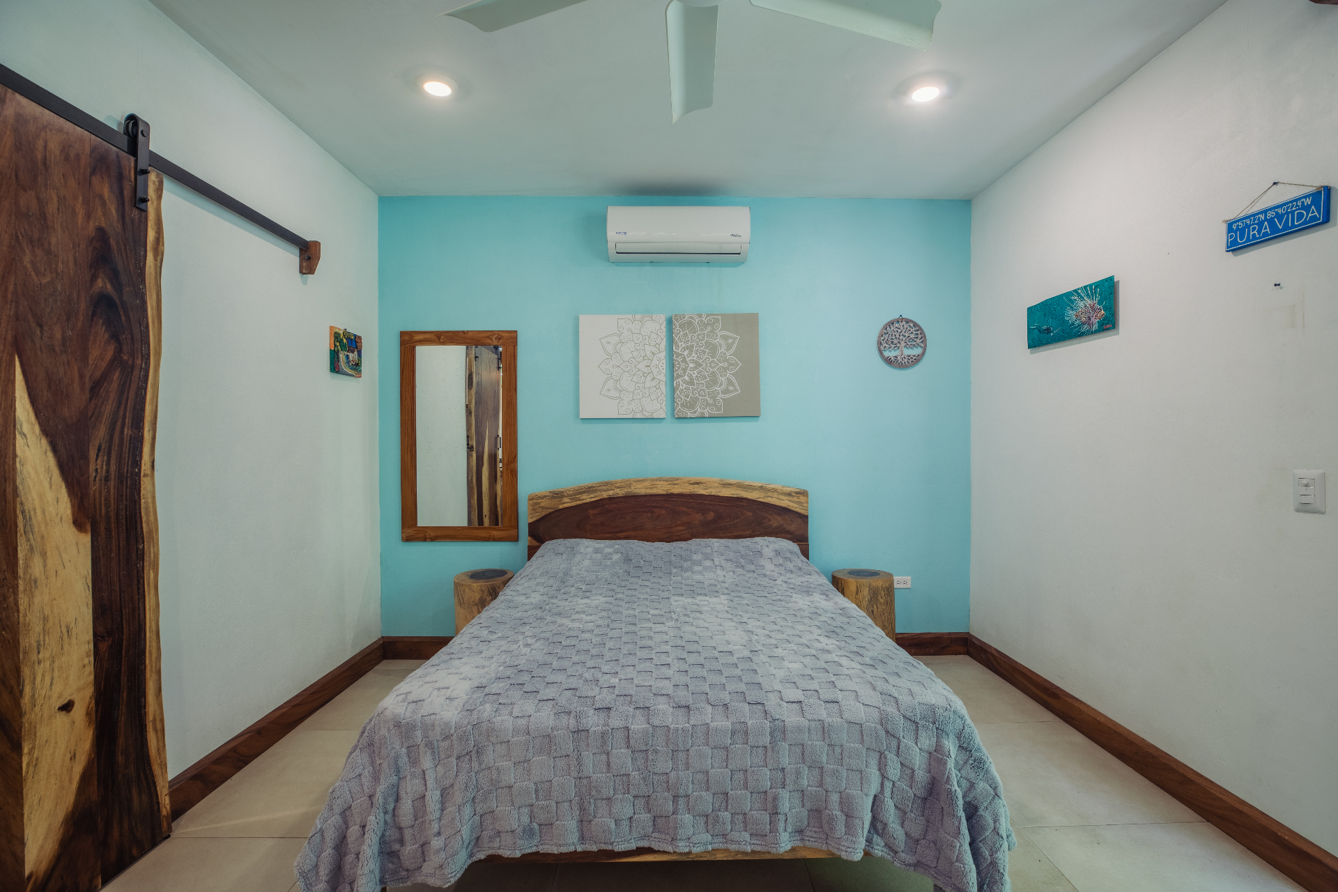 Studio Reina queen bed with turquoise accent wall, live-edge headboard, and garden views at Hacienda Nosara