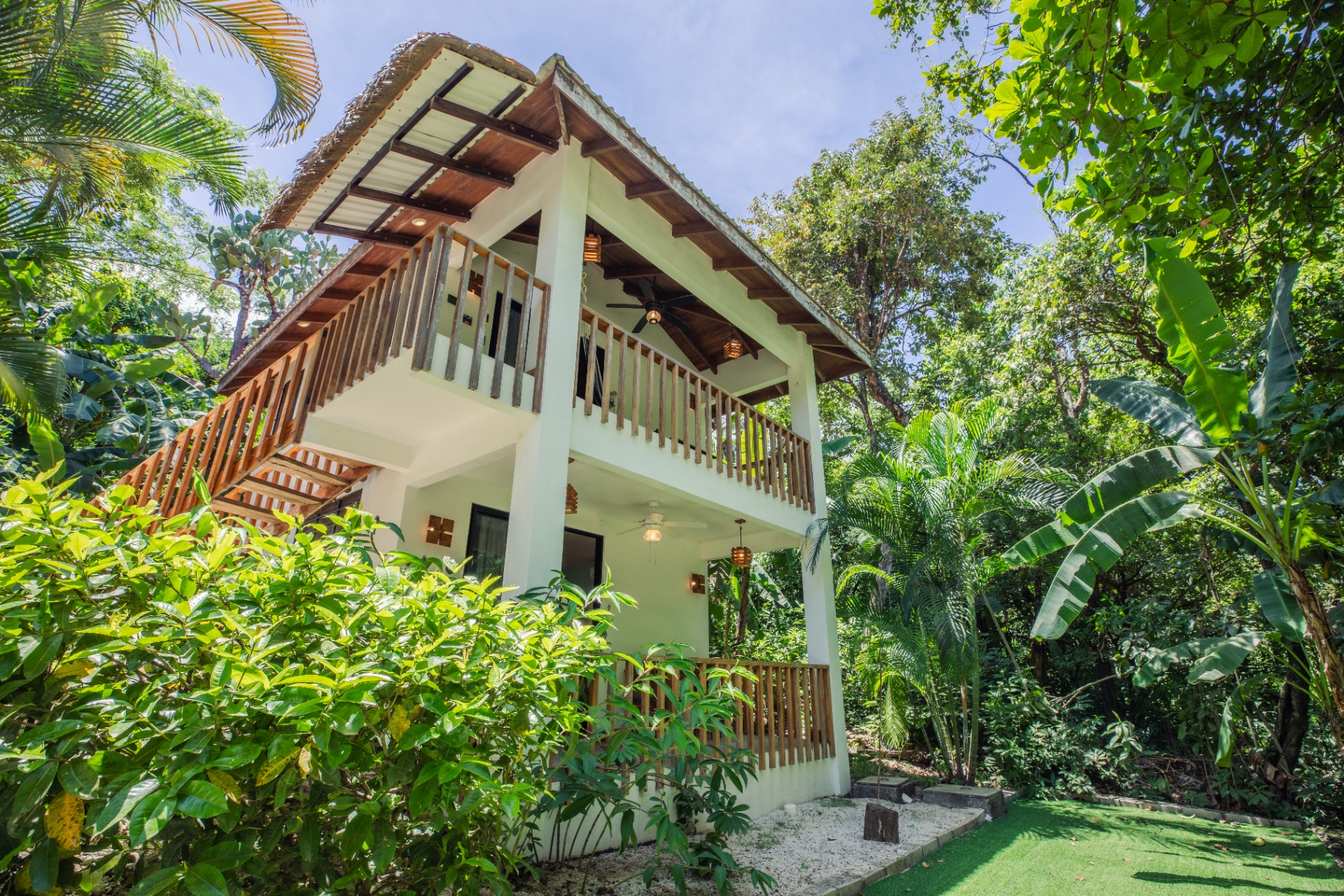 Studio Rey exterior — two-story white casita with wooden balcony framed by tropical canopy at Hacienda Nosara